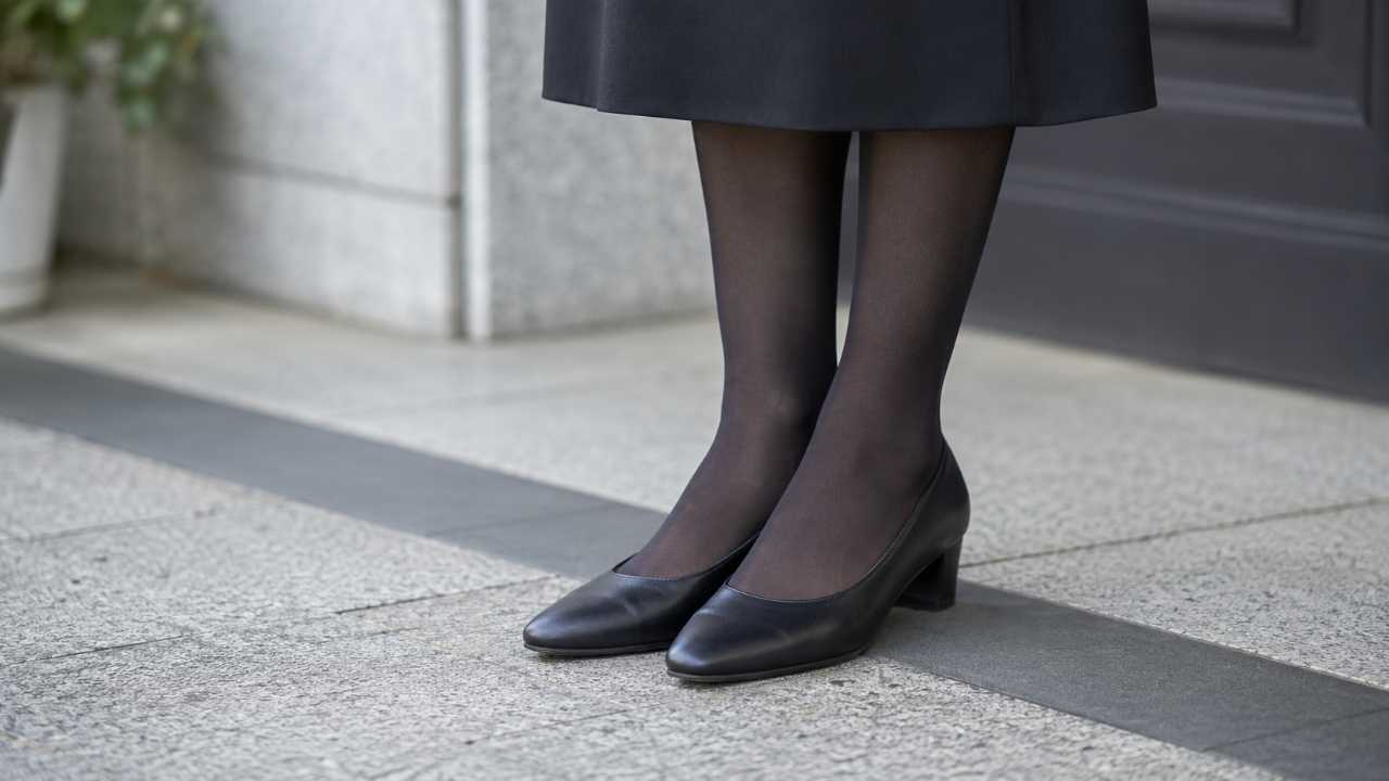 黒ストッキングと黒パンプスを合わせた女性の足元, 喪服の裾が少し見える構図